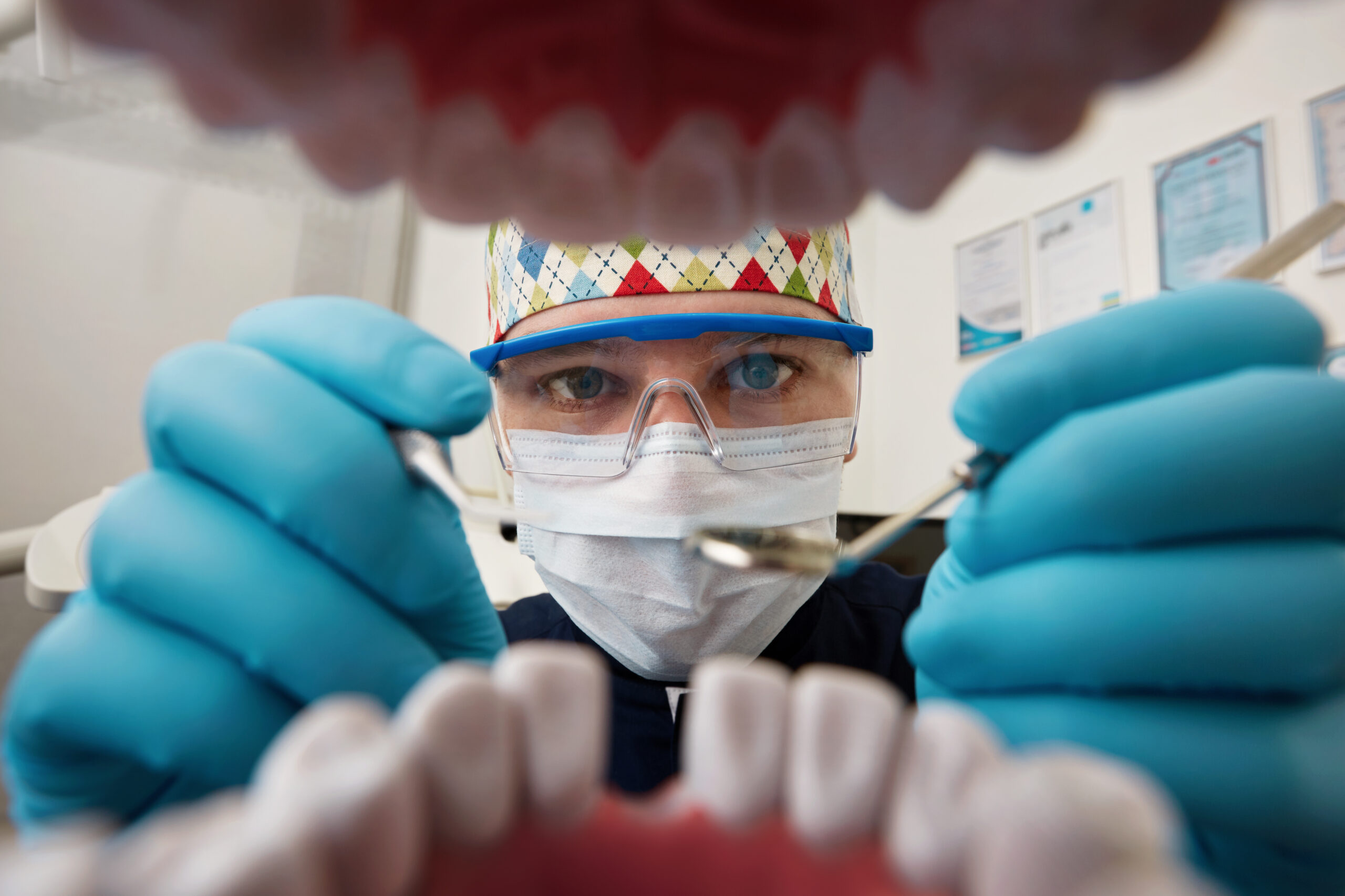 Healthy teeth and smile. Serious doctor directly into the camera. Dentist sitting in the dentist for dental chair and holding a dental drill in hand.